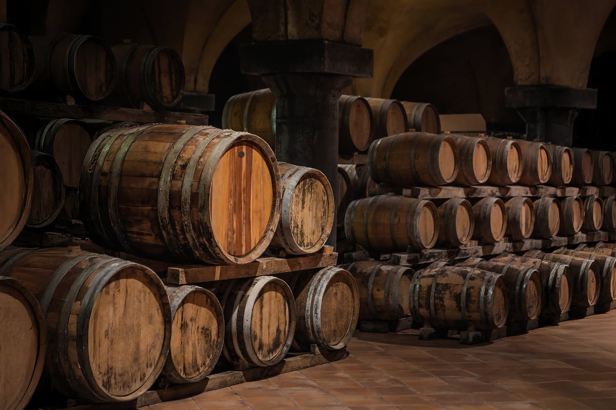 Traditional cellar with stacked wood barrels aging wine in warm atmosphere.