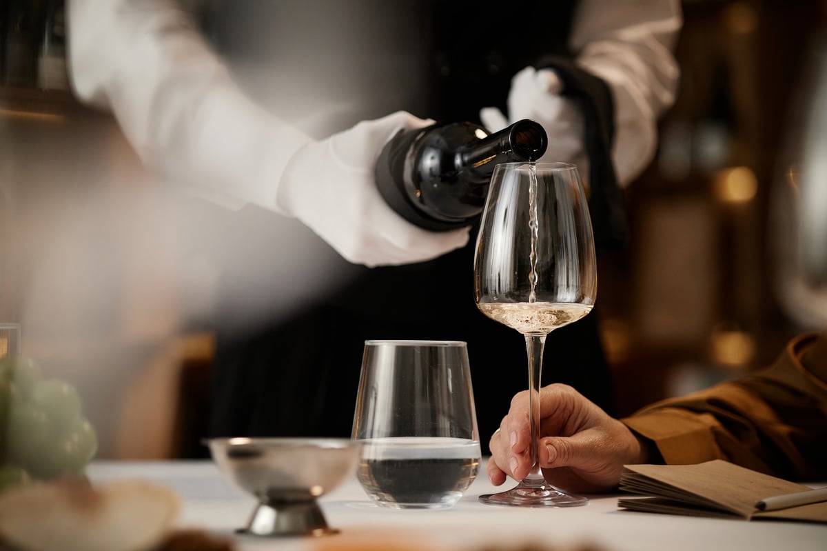 Sommelier sirviendo vino durante una cata, servicio de atención personalizada