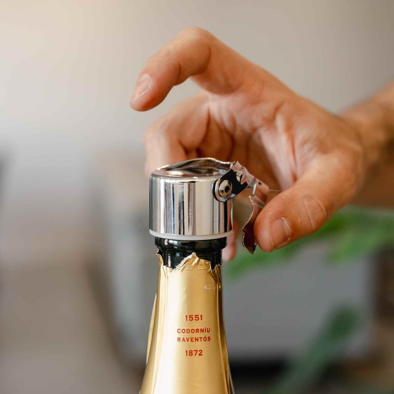 Hand opening a champagne bottle with wire cage and foil wrapper