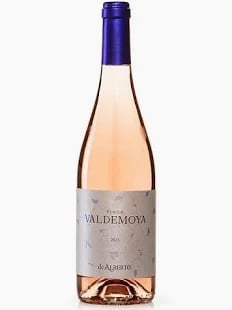 Bottle of Valdemoya rosé wine with blue foil cap and light pink liquid against white background