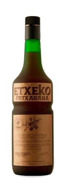 Bottle of Etxeko Patxaran liqueur with black cap and tan label on white background