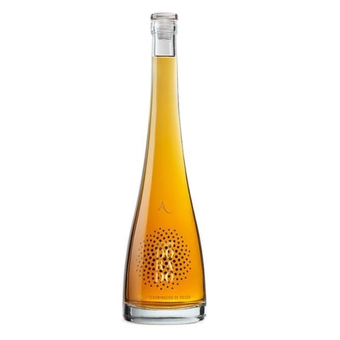 Tall glass bottle of golden amber liquid with cork top against white background